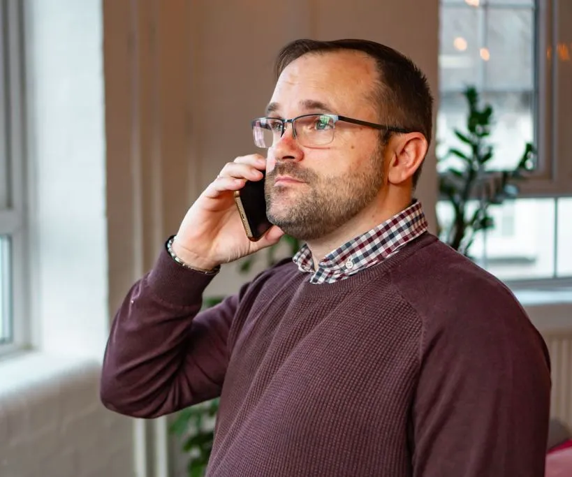 Rehabs UK Senior Treatment Advisor Scott Ardley is on the phone discussing aftercare support for addiction treatment