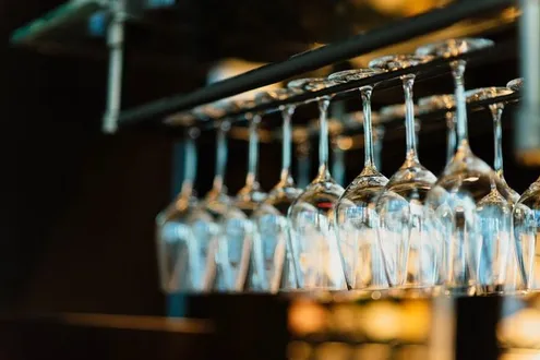 A row of upturned wine glasses are hanging up from a ceiling in a bar