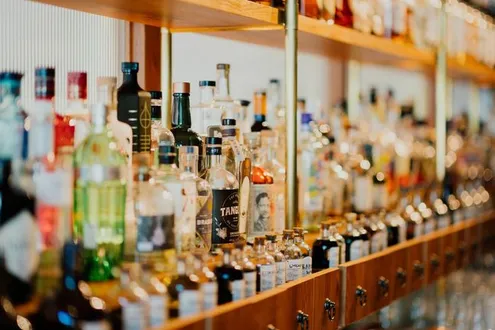 Bottles of alcohol mainly spirits are standing in rows in a brightly lit bar