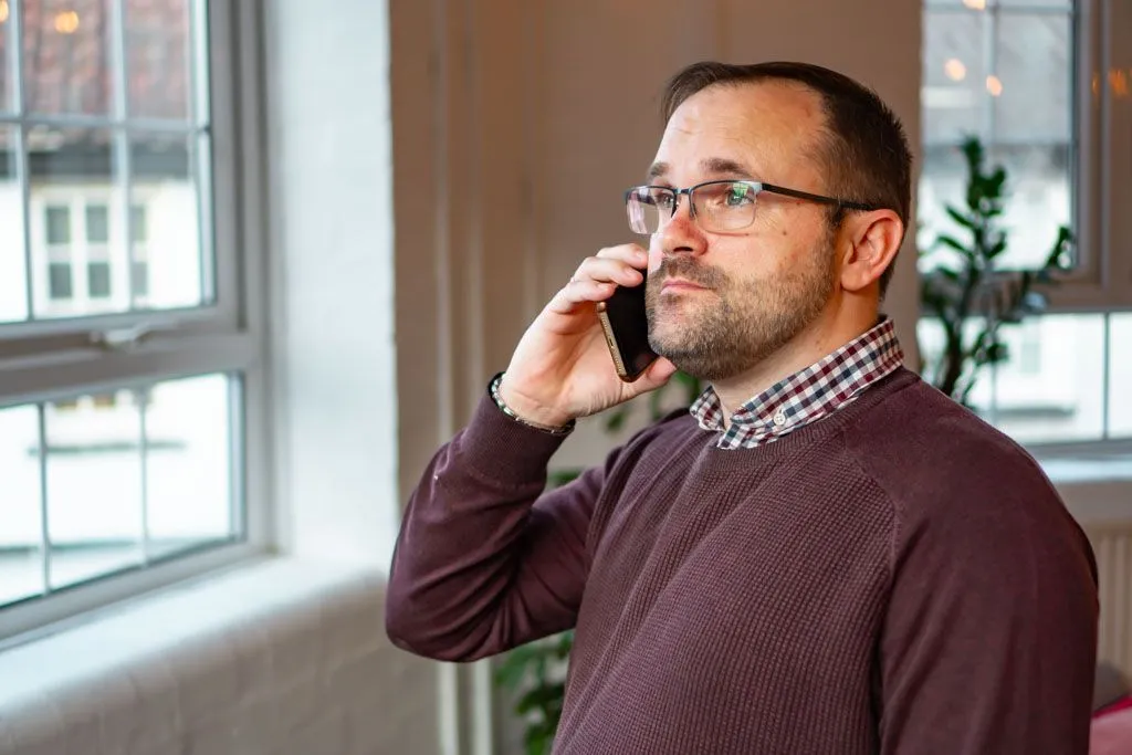 Rehabs UK Senior Treatment Advisor Scott Ardley is on the phone discussing aftercare support for addiction treatment
