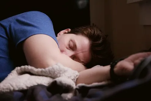 A man is laid sleeping with his arm outstretched highlighting the problems cocaine can cause on sleep