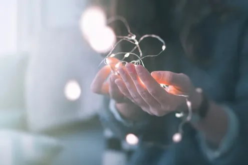 Female outstretched hands hold fairy lights representing hope and relapse prevention