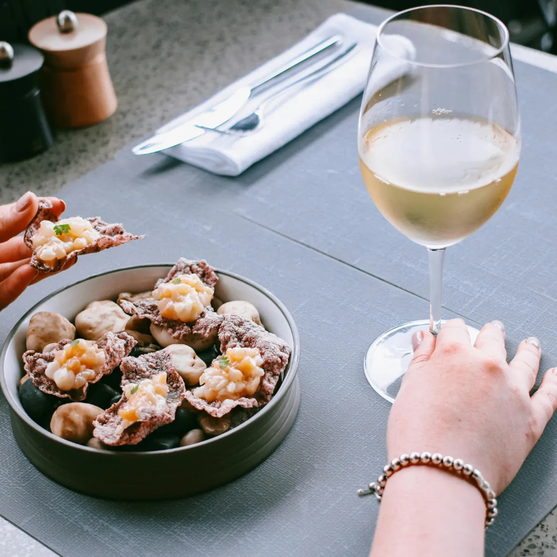 hand holding glass of wine and a bowl of food