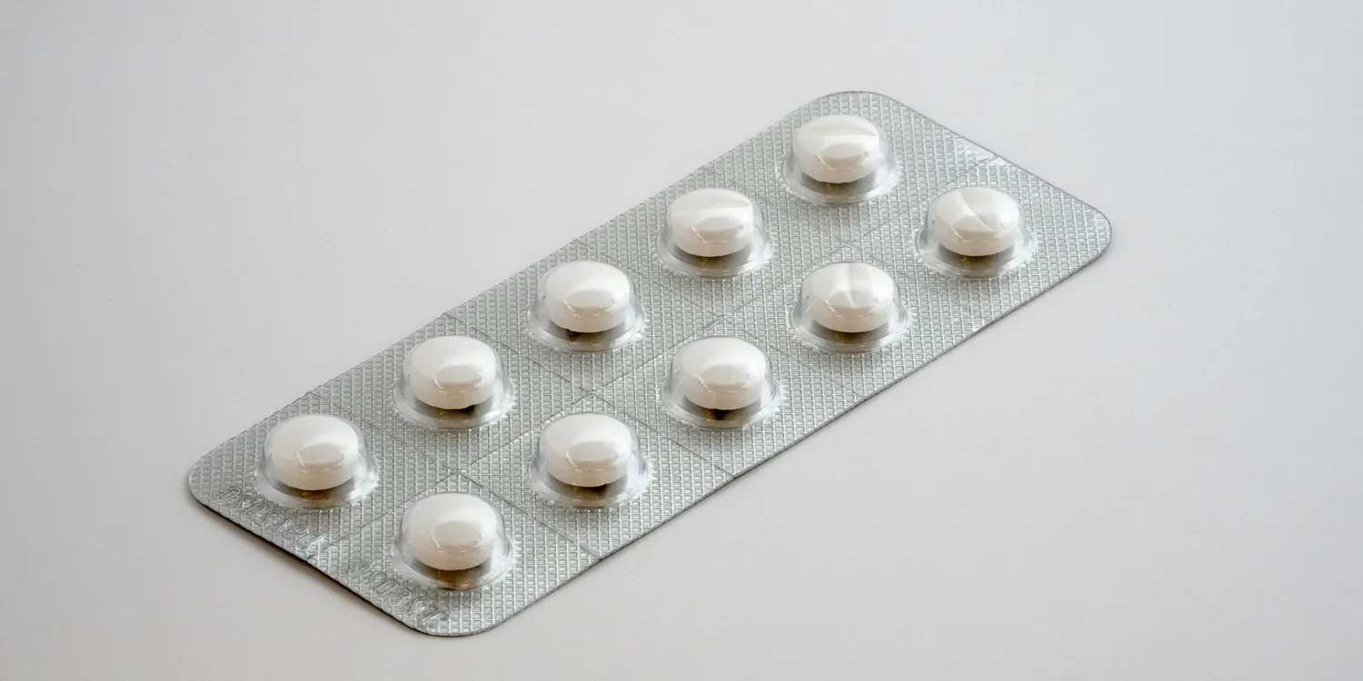 Blister pack containing white round tablets on a plain white background.