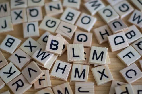 Wooden tiles with letters on are sprawled across a table representing an A to Z Glossary of drugs