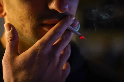 A man is smoking cocaine and the smoke is filling the air highlighting how smoking cocaine can impact the lungs