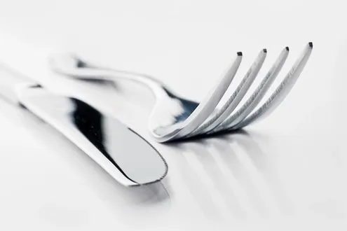 A silver knife and fork lay on a table representing the struggle of disordered eating