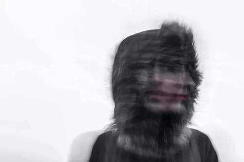 Blurred image of a person wearing a parker coat with their hood up depicting the link between trauma and addiction