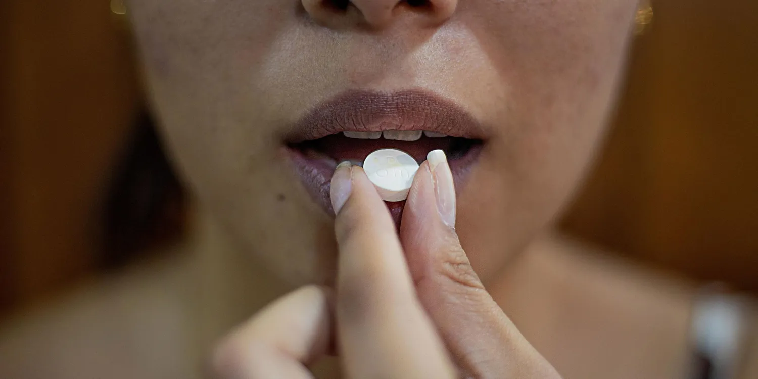 Women taking a sleeping pill - Online searches for sleeping pills rise 83% - why do so many struggle with sleepless nights?