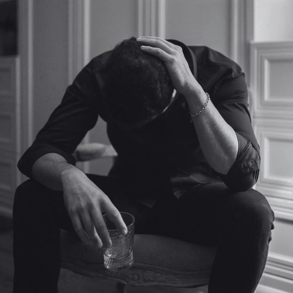 black and white photo showing man leaning forward with empty glass